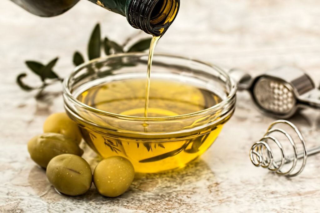 Olivenoel wird in eine Schale gegossen Olivenöl Muskelaufbau Richtige Ernährung fürs Fitnesstraining