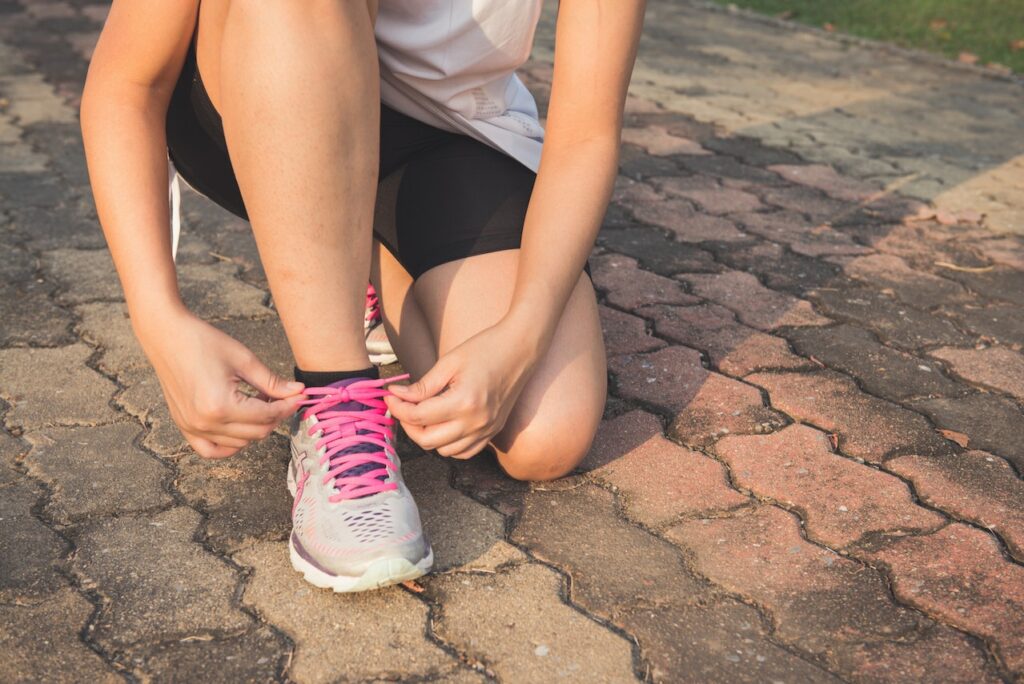 junge Frau bindet sich die Schuhe Welche Nahrungsergänzungsmittel können für Läufer sinnvoll sein
